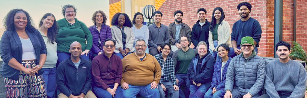 Mga miyembro ng kawani ng Bridge HIV na nakatayo nang sama-sama sa isang pader na ladrilyo.